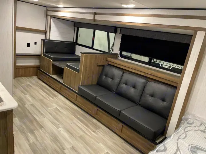 Step inside this RV rental, showcasing a functional living area with a raised dinette and a plush, multi-seat sofa.. Heartland RVs Pioneer Trail Blazer 2022