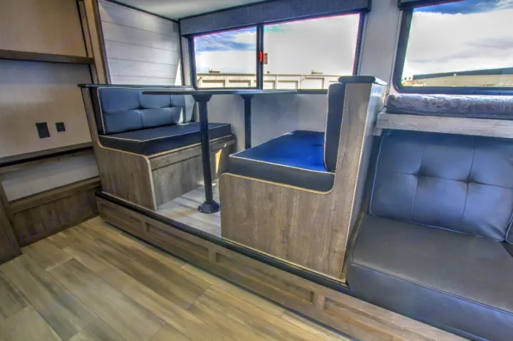 RV rental interior: a cozy dinette with black padded benches, a table, and a partial view of a sofa/bunk area.. Heartland RVs Pioneer Trail Blazer 2022