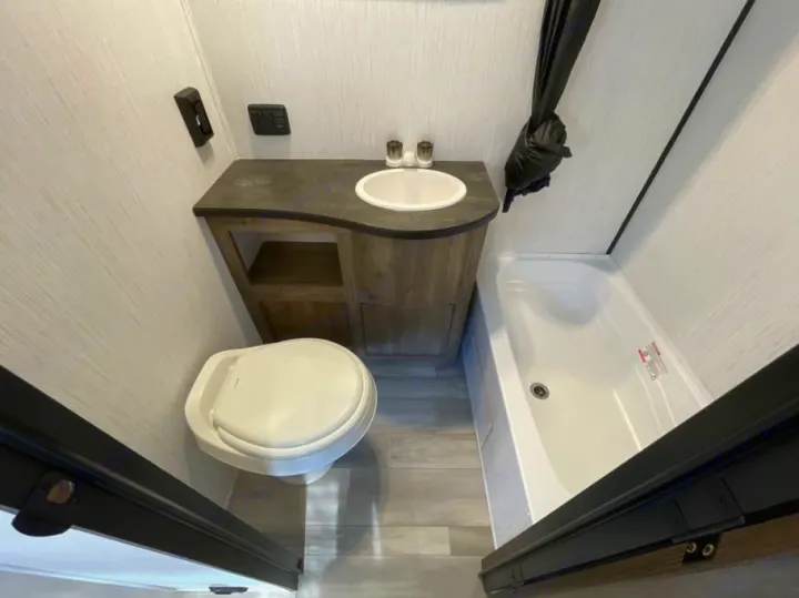 Compact RV rental bathroom with toilet, vanity sink, and a small tub/shower, providing essential amenities.. Heartland RVs Pioneer Trail Blazer 2022