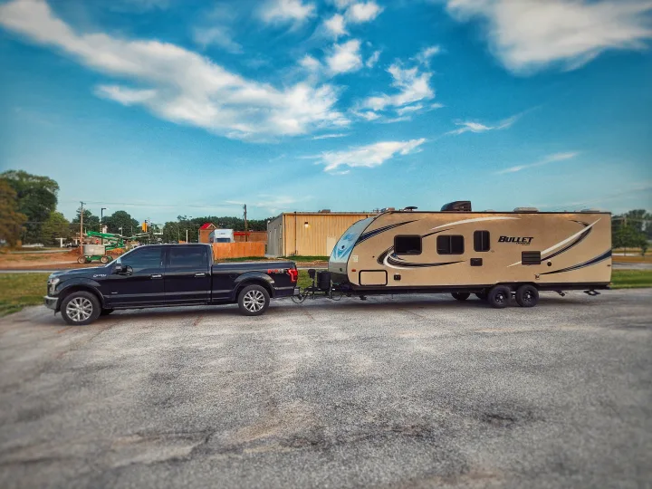 Ford F-150 truck hitched to a tan travel trailer. Experience outdoor adventure with an RV rental for your next trip.. Keystone Bullet 2017