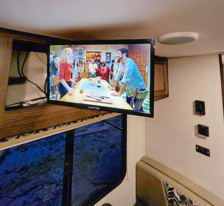 An RV rental interior featuring a TV displaying a show, with a comfortable seating area and a window for scenic views.. Keystone Bullet 2017