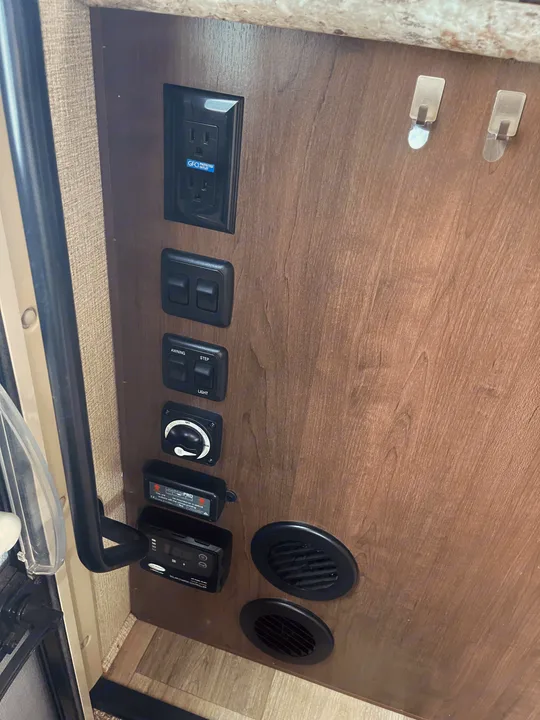 RV rental interior control panel with GFCI outlet, awning/step/light switches, solar charger, and vents for convenience.. Thor Motor Coach Freedom Elite 2019