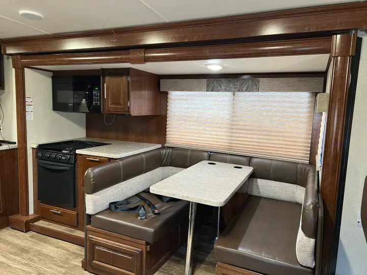 Spacious RV rental interior featuring a full kitchen with microwave and stove, plus a cozy dinette booth with a table.. Other Other 2018