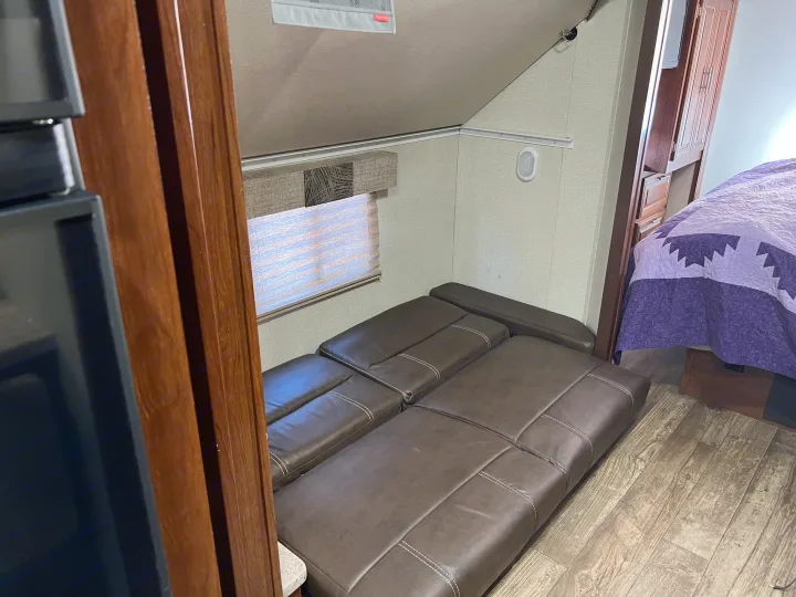 Brown modular sofa/bed in an RV rental living area, with wood floors and a glimpse of a private bedroom.. Other Other 2018
