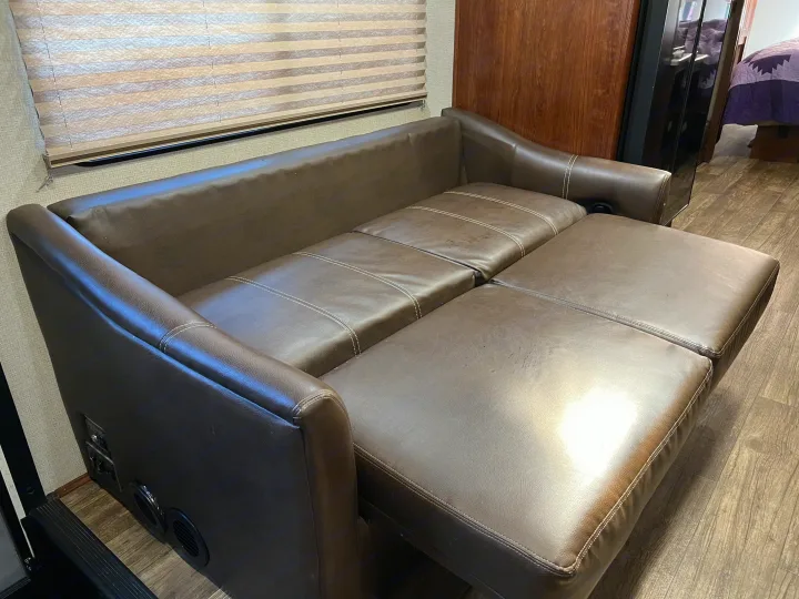 RV rental: Brown leather sofa bed, partially extended, inside an RV with wood-look flooring and pleated window blinds.. Other Other 2018