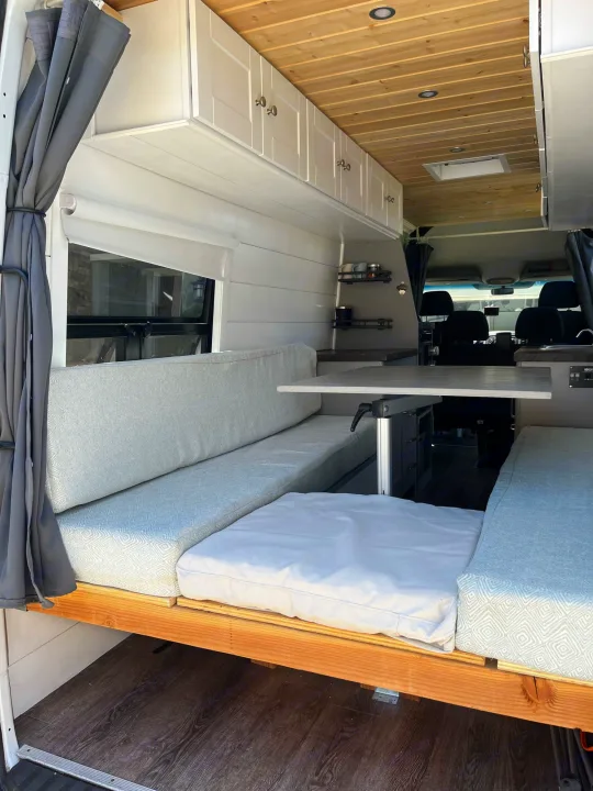Modern RV rental interior showcasing a convertible dinette, adjustable table, kitchen, and extensive overhead storage.. Mercedes-Benz Sprinter 2013