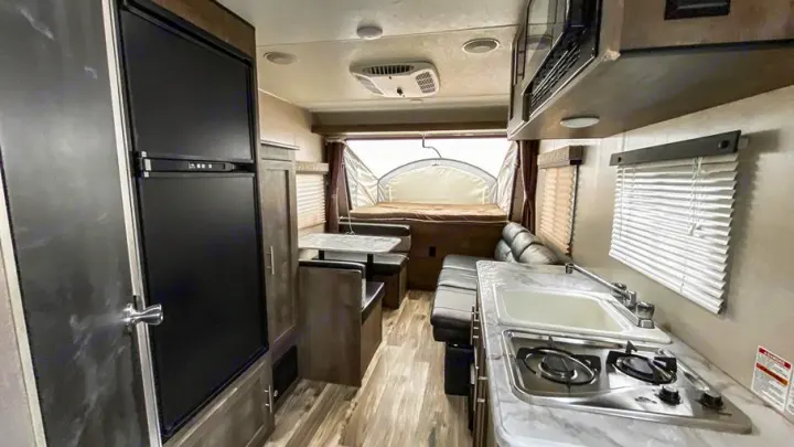 Inside this RV rental: kitchen with stove/sink, dining booth, comfy seating, and cozy pop-out bed. Ready for adventure!. K-Z Manufacturing Escape 2017