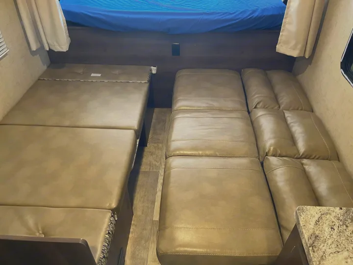 Spacious RV rental interior with a convertible dinette and reclining sofa, maximizing comfort and function.. K-Z Manufacturing Escape 2017