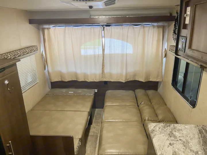 RV rental interior featuring a convertible bed, comfortable seating, and curtained windows, ideal for travel.. K-Z Manufacturing Escape 2017