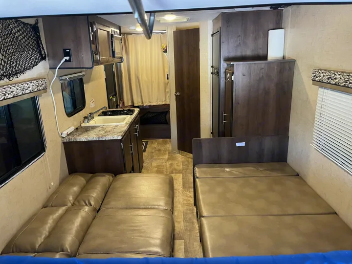RV rental interior featuring a compact kitchenette, flexible leather-look seating, and convertible beds.. K-Z Manufacturing Escape 2017