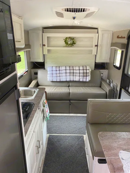 Modern RV rental interior: cozy living space with kitchen, sofa, and dining booth. Perfect for adventures!. Forest River Rockwood 2020
