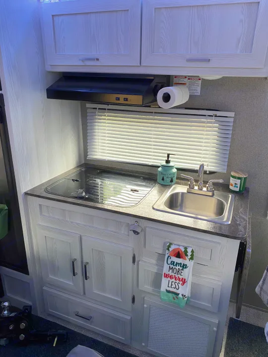 Explore this RV rental's efficient kitchen: cooktop, sink, cabinets, and thoughtful camping decor.. Forest River Rockwood 2020
