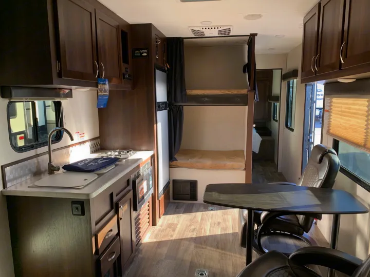 Step inside this RV rental, showcasing a well-equipped kitchen, comfortable bunk beds, and a dining space. Ideal for travel.. Jayco Octane 2019