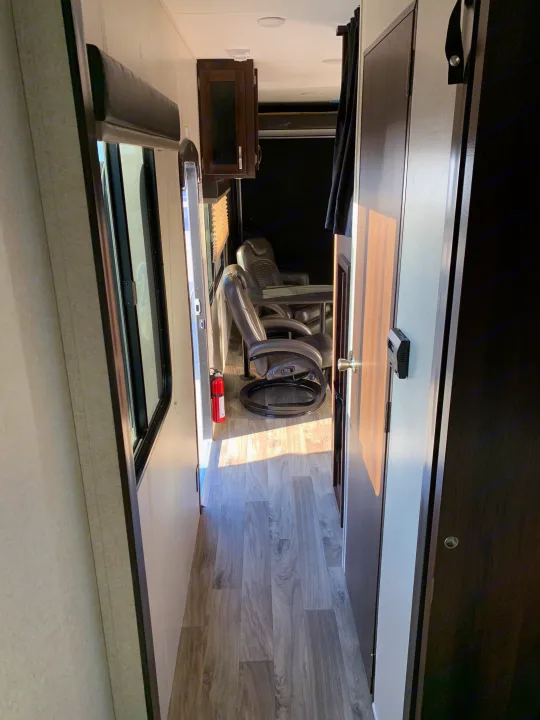 RV rental interior: a bright hallway with wood-look floors leads to a spacious living area with two plush chairs and cabinets.. Jayco Octane 2019
