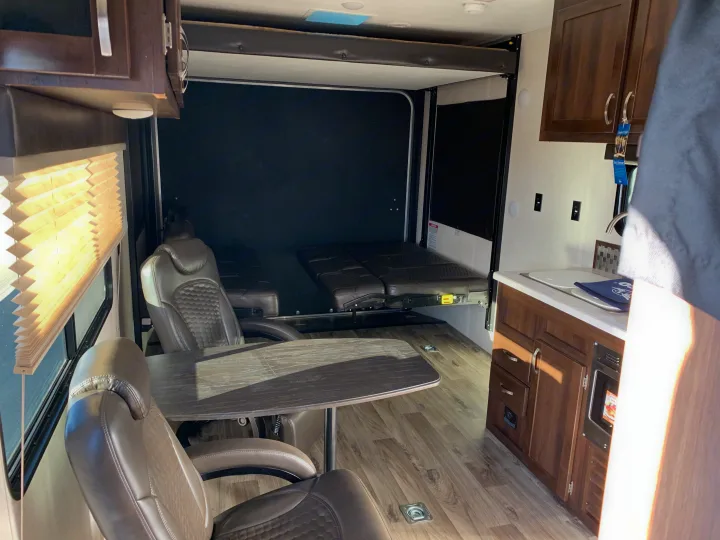 Bright RV rental interior: dining area, versatile rear with fold-down beds/seats, and a full kitchen. Ready for travel.. Jayco Octane 2019