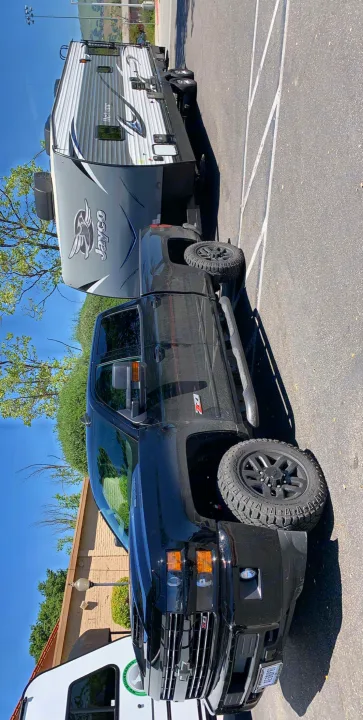 Black Chevy pickup truck hitched to a grey Jayco RV, ideal for an RV rental adventure. Parked under clear skies.. Jayco Octane 2019