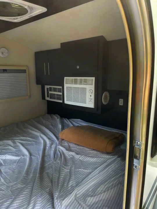 This RV rental interior features a cozy bed, dual AC units for climate control, and smart storage. Perfect for your trip.. nuCamp RV T@G XL 6 wide 2022
