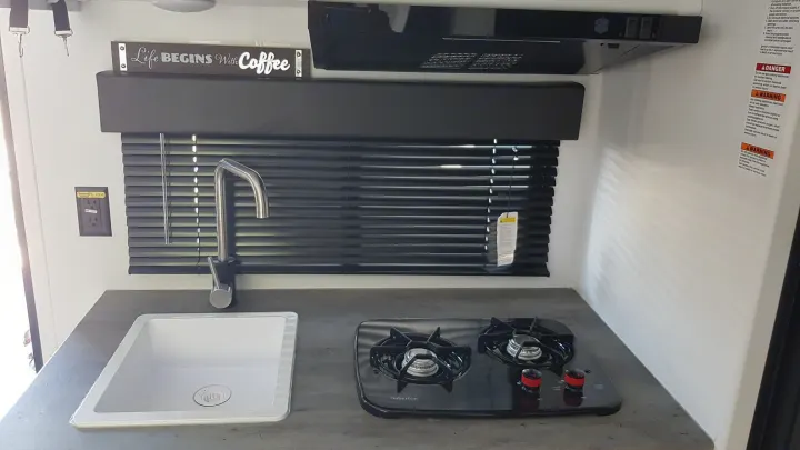 Compact RV rental kitchen with sink, gas stove, and "Life BEGINS With Coffee" sign, perfect for travel adventures.. Keystone RV Hideout 2022