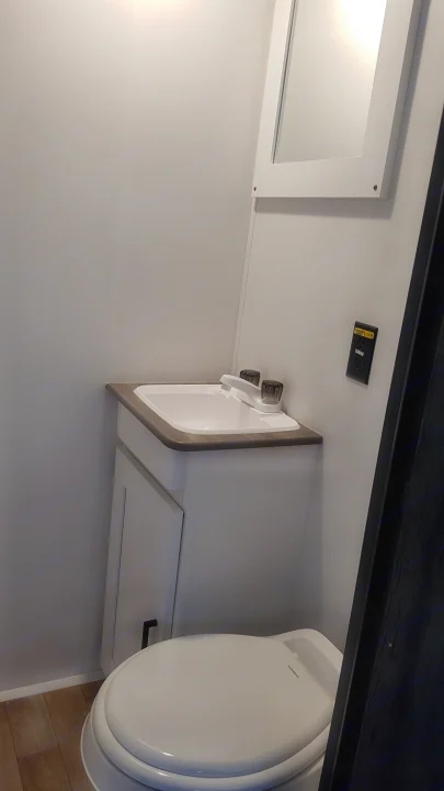 This RV rental's compact, bright bathroom features a sink, toilet, and mirrored cabinet.. Keystone RV Hideout 2022