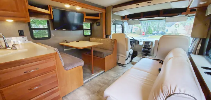 Inside an RV rental: a modern interior with kitchen, dinette, and living area, plus the driver's cockpit visible.. Winnebago Vista 2016