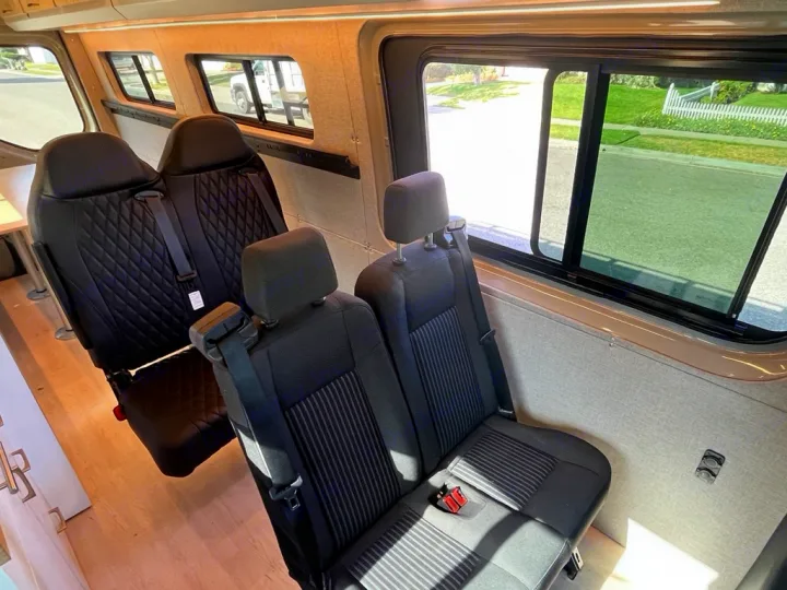 Spacious RV rental interior with comfy multiple-row seating, ideal for group travel & van life adventures.. Mercedes Sprinter 2021