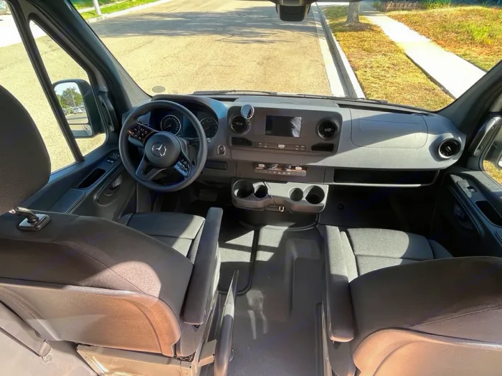 View into an rv rental van's cockpit, showing Mercedes-Benz steering wheel, dashboard, and spacious front area.. Mercedes Sprinter 2021