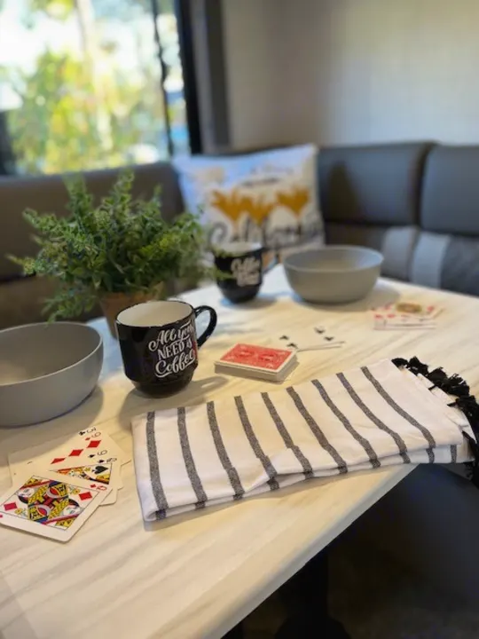 RV rental interior ready for fun: coffee, cards, and comfy seating by a window with greenery.. Forest River Wildwood X-Lite 2022