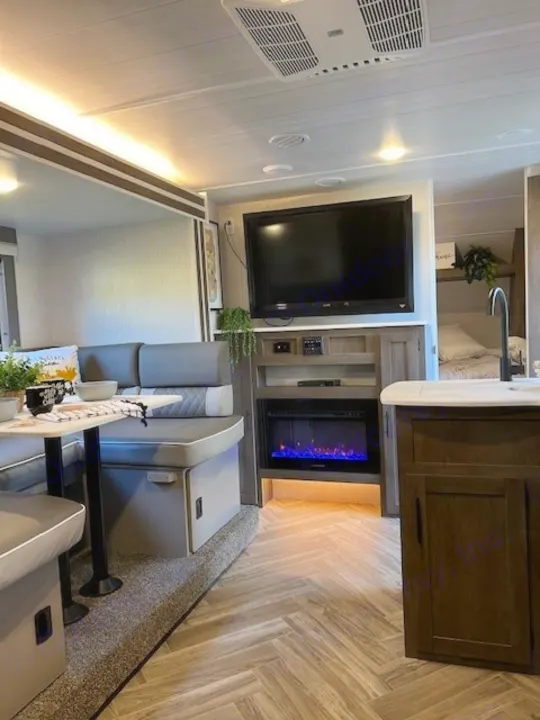 Modern RV rental interior: comfortable living space with dining booth, TV, electric fireplace, and kitchen.. Forest River Wildwood X-Lite 2022