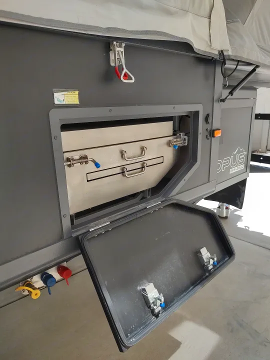 Sink and Stove compartment. Water and propane connections are also visible.. Opus Camper Opus Camper Popup Trailer 2021