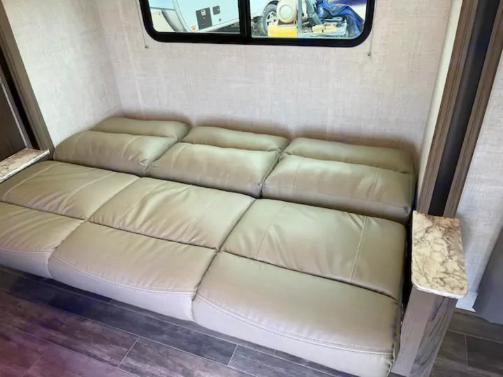 Enjoy comfortable seating in this RV rental! Light sofa converts to a bed, with side tables & large window.. Gulf Stream 21QBS 2022