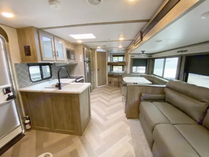 Inside an RV rental: a spacious living area with a kitchen island, U-shaped dinette, comfortable sofa, and bunk beds further back.. Forest River Salem Hemisphere HL 2021