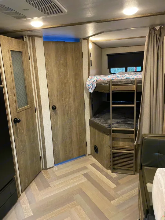 Modern RV interior: bunk beds with ladder and storage beneath, set on herringbone flooring. Perfect for your rv rental trip.. Forest River Salem Hemisphere HL 2021