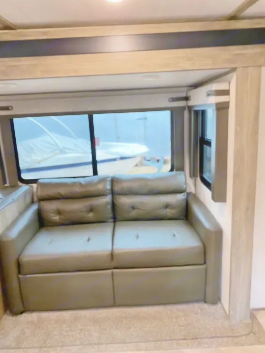 RV rental interior: comfortable dark gray upholstered seating by a large window. An inviting space for your travels.. Forest River Salem Hemisphere HL 2021