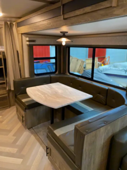 RV rental dinette shows gray booth seating, a modern table, and large windows. Enjoy comfort on your travels.. Forest River Salem Hemisphere HL 2021