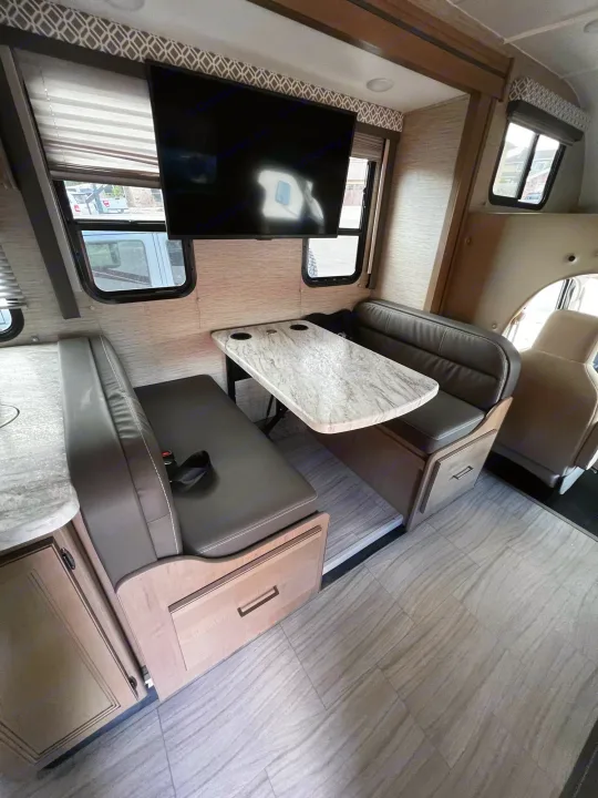 Modern RV rental dinette featuring a table, plush bench seats, TV, and light flooring.. Coleman Other 2022