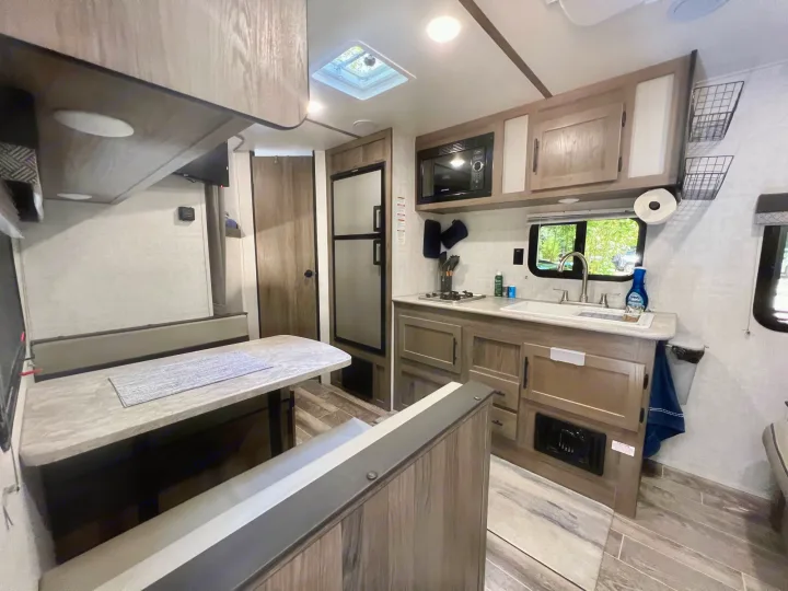 Spacious RV rental interior featuring a modern kitchen, dinette area, and comfortable living space, ideal for travel.. Gulf Stream Amerilite 2022