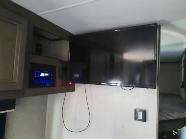 Inside an RV rental: entertainment system with blue lights, wall-mounted TV, and a cozy bunk bed.. Jayco Jay Flight SLX 2019