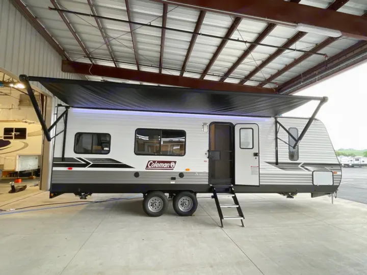 Silver & grey Coleman travel trailer, awning extended, steps down. Ready for an RV rental adventure.. Coleman 270TQ 2022