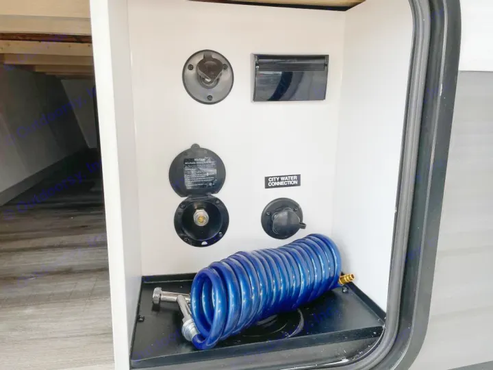 RV rental utility bay with city water connection, fresh water fill inlet, and a blue coiled hose for outdoor use.. Coleman 270TQ 2022