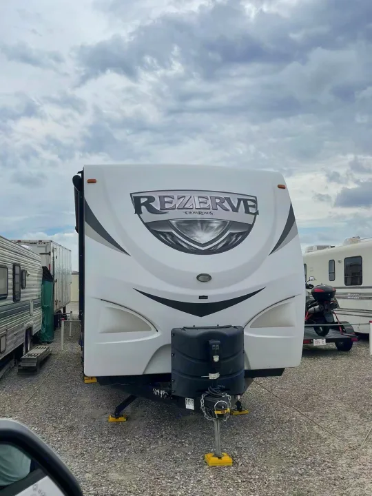 Front view of a white Rezerve travel trailer, ready as an rv rental, parked on gravel under cloudy skies.. Crossroads RV Rezerve 2016
