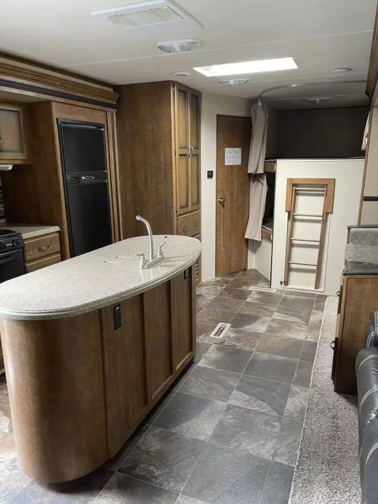 Spacious RV rental interior featuring a kitchen island, refrigerator, and bunk beds for family comfort.. Crossroads RV Rezerve 2016