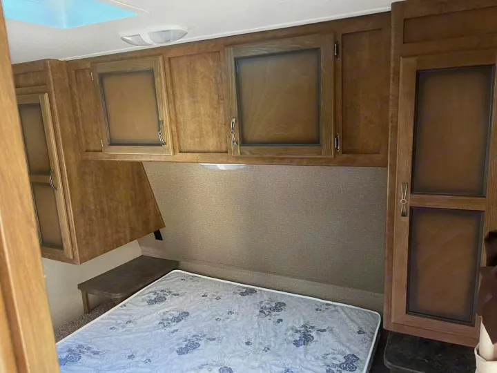 RV rental interior: cozy bedroom with overhead cabinets, a comfortable bed, and convenient storage for your travels.. Crossroads RV Rezerve 2016