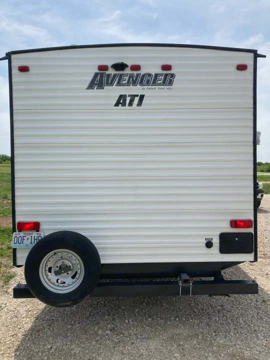Rear view of a white Avenger travel trailer, perfect for your next RV rental adventure. Spare tire and Missouri license plate visible.. Avenger ATI 2018