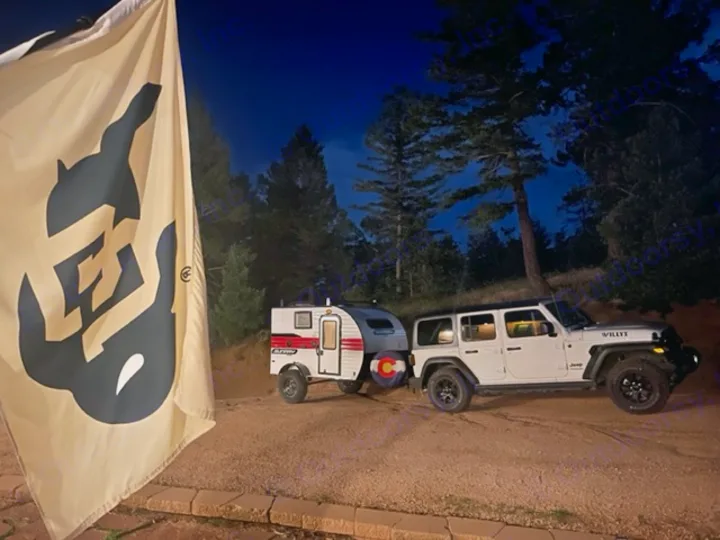 CU flag, white Jeep, & RV rental trailer parked at dusk. Ready for Colorado camping adventure.. Sunset Park RV SunRay 2020