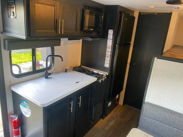Modern RV rental interior: kitchen with sink, stove, microwave, fridge, and ample storage for your travels.. Forest River Wolf Pup 2021