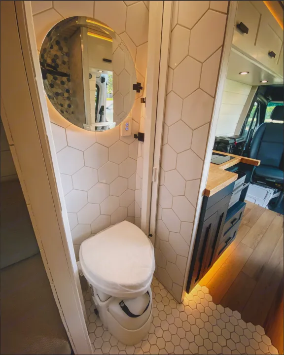 This RV rental interior features a chic van bathroom with a composting toilet, hexagonal tiles, & modern kitchenette.. Mercedes-Benz Sprintervan 2019