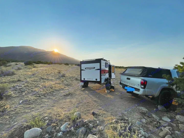 Experience the freedom of an RV rental: a travel trailer and pickup truck at sunset in a vast desert.. Sunset Park RV SunRay 2020