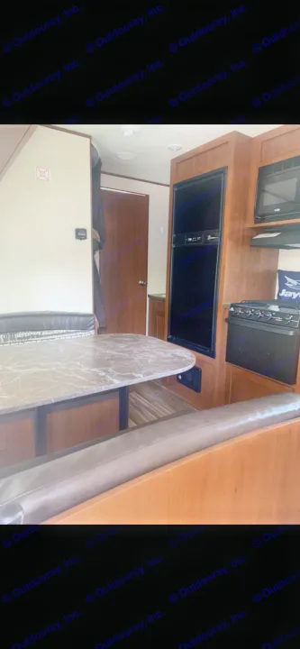 Experience this RV rental's interior: a compact kitchen with fridge, microwave, stove, and comfortable dinette area.. Jayco Jay Flight 2017