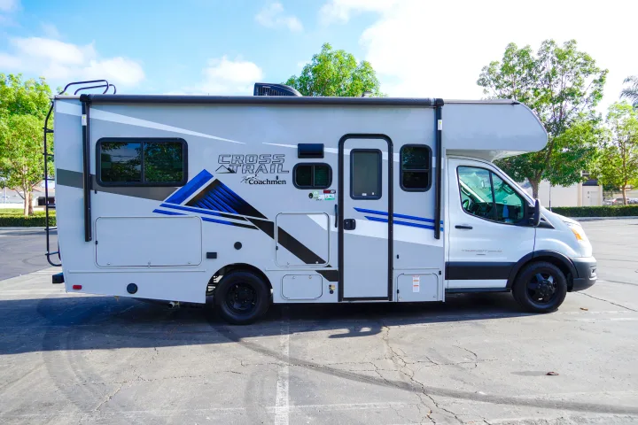 A modern white and gray Class C Coachmen Cross Trail RV rental, featuring striking blue accents, parked outdoors, inviting road trip adventures.. Forest River Coachmen Cross Trail XL 2022