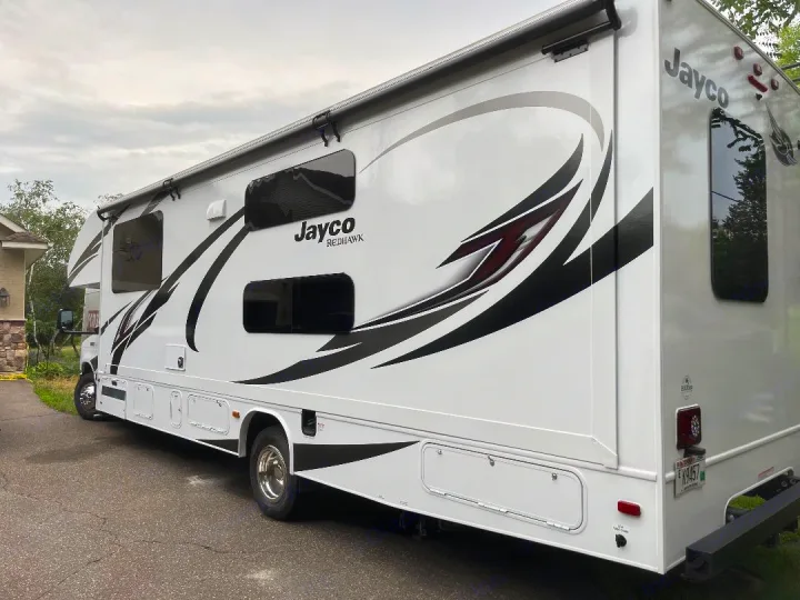 A clean white Jayco Redhawk motorhome, an ideal RV rental, parked on a paved drive, ready for your next road trip adventure.. Jayco Redhawk 2021